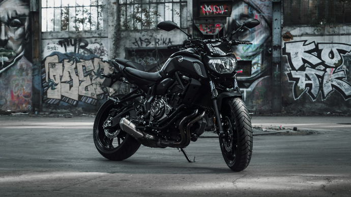 a black motorcycle parked in front of a graffiti covered wall